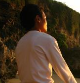 A woman sitting on a rock next to a body of water